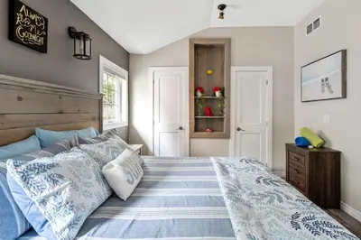 a bedroom with a bed with blue and white pillows at Sandy Cove Cottage in Crystal Beach