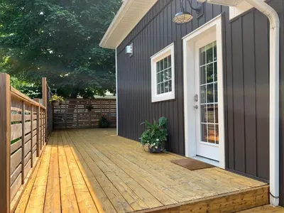 a deck with a black house and a white door at Sandy Cove Cottage in Crystal Beach