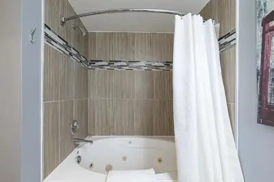 a bath tub with a shower curtain in a bathroom at Condo at Blue Mountain on Ski Run Close to Village in Blue Mountains