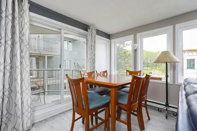 a dining room with a table and chairs and windows at Condo at Blue Mountain on Ski Run Close to Village in Blue Mountains