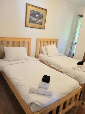 two beds with towels and a hat on them at Mountain Trail-Smart TV-Self Check-In-Full Kitchen-Balcony-BBQ in Blue Mountains