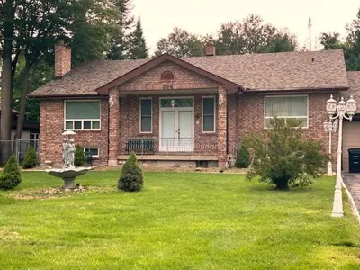 a brick house with a porch and a grass yard at Leslie in Wasaga Beach