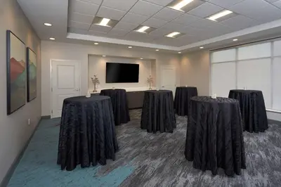 a conference room with four tables in front of a screen at TownePlace Suites by Marriott Hamilton in Hamilton
