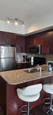 a kitchen with a granite counter top with a sink and chairs at Toronto CN Tower Maple Leaf Square Luxurious 2 Bedroom Condo in Toronto
