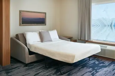 a bed in a room with a couch and a window at Fairfield by Marriott Inn & Suites Orillia in Orillia