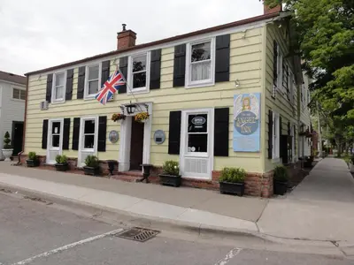 a yellow building with an american flag on it at The Olde Angel Inn in Niagara on the Lake