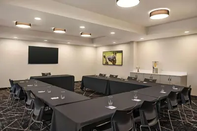 a conference room with tables and chairs and a screen at Microtel Inn & Suites by Wyndham Aurora in Aurora