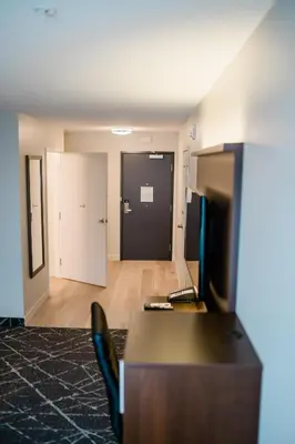 a room with a desk and a hallway with a door at Microtel Inn & Suites by Wyndham Aurora in Aurora