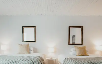 two beds in a white room with two mirrors at The Kent Motel in Niagara on the Lake