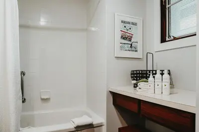 a white bathroom with a tub and a sink at The Kent Motel in Niagara on the Lake