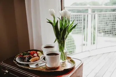 a table with two cups of coffee and a vase of flowers at The Kent Motel in Niagara on the Lake
