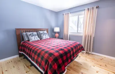 a bedroom with a bed with a plaid blanket and a window at 4 Bedroom Rustic Chalet in Blue Mountains