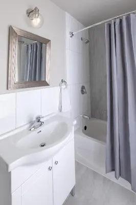 a white bathroom with a sink and a bath tub at 4 Bedroom Rustic Chalet in Blue Mountains