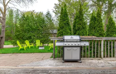 a grill on a patio with chairs and trees at 4 Bedroom Rustic Chalet in Blue Mountains