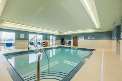 a swimming pool in a building with blue chairs at Holiday Inn Express & Suites - Welland in Welland