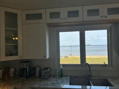 a kitchen with a view of the ocean from a window at Entire waterfront cottage in carrying place in Carrying Place