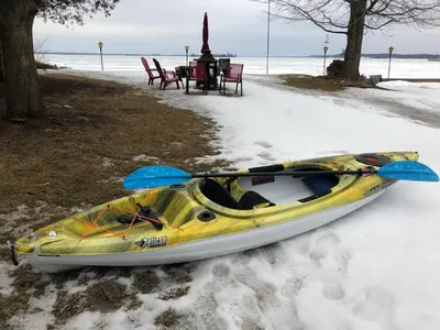 a yellow kayak sitting in the snow next to a table at Entire waterfront cottage in carrying place in Carrying Place