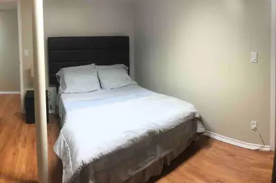 a small bedroom with a bed with white sheets at 3 Spacious Bedroom Basement Apartment in Richmond Hill in Richmond Hill