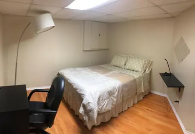 a bedroom with a bed and a desk and a lamp at 3 Spacious Bedroom Basement Apartment in Richmond Hill in Richmond Hill