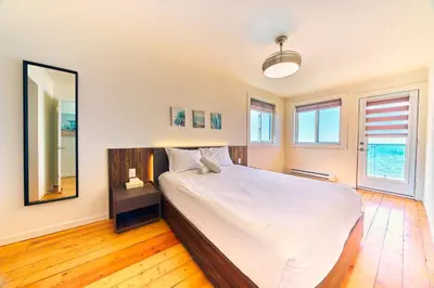 a bedroom with a large bed and a mirror at The Long Beach Resort - Beachfront Cottages & Townhouse Suites in Wainfleet