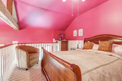 a bedroom with pink walls and a bed and a chair at School House Bed and Breakfast C.1859 in Niagara on the Lake