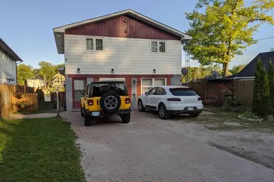 a jeep and a car parked in front of a house at Cottage with River Front & minutes away from Beach in Wasaga Beach