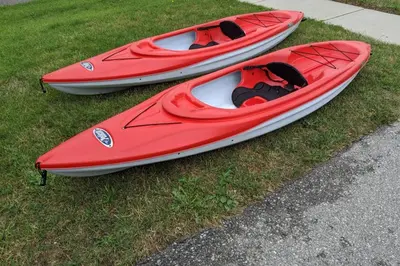 three kayaks sitting on the grass next to a sidewalk at Cottage with River Front & minutes away from Beach in Wasaga Beach