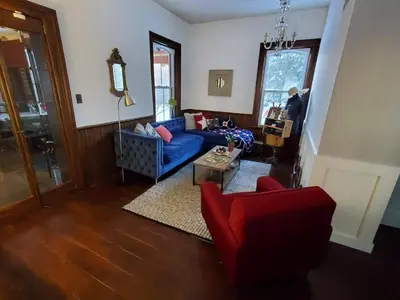 a living room with a blue couch and red chairs at A rustic cabin in the woods in Orangeville