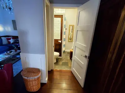 a bathroom with a toilet and a hallway with a door at A rustic cabin in the woods in Orangeville
