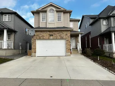 a house with a white garage door in a driveway at Comfortable room B in Kitchener
