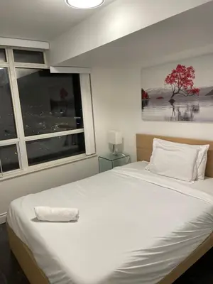 a white bed in a room with a window at PlanURstay in Mississauga