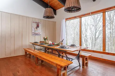 a dining room with a wooden table and benches at Blue Mtn Chalet with a Sauna, Sleeps 20 in Blue Mountains