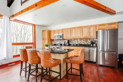 a kitchen with wooden cabinets and a stainless steel refrigerator at Blue Mtn Chalet with a Sauna, Sleeps 20 in Blue Mountains