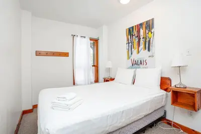 a white bedroom with a large bed with white sheets at Blue Mtn Chalet with a Sauna, Sleeps 20 in Blue Mountains