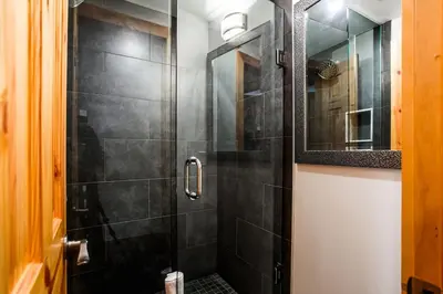 a bathroom with a shower with a glass door at Blue Mtn Chalet with a Sauna, Sleeps 20 in Blue Mountains