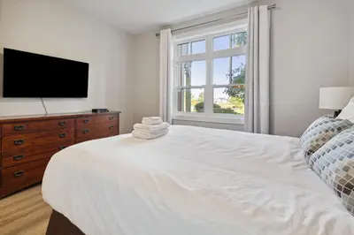a white bedroom with a large bed and a flat screen tv at 2 Bedroom Condo only steps to the Village! in Blue Mountains