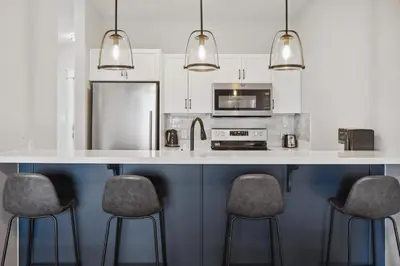 a kitchen with a white counter with four bar stools at 2 Bedroom Condo only steps to the Village! in Blue Mountains