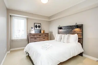 a bedroom with a large bed with a wooden headboard at 3 Bedroom Mountain Walk Condo, Steps to Village in Blue Mountains