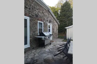 a barbecue on a patio next to a brick building at Arrowstone Farmhouse in Historic Old Town in Niagara on the Lake