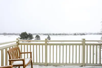 a snowy porch with two chairs and a fence at 2 Bedroom Rivergrass with a View in Blue Mountains