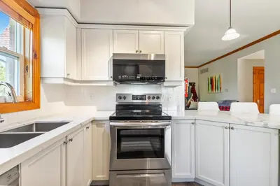 a kitchen with white cabinets and a stove top oven at Blue Mountain 3 bedroom Dream Chalet 81590 in Collingwood