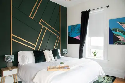a bedroom with a white bed with a green wall at The Juniper Inn in St. Catharines