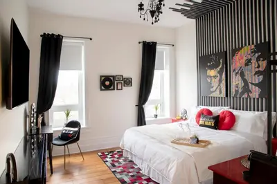 a bedroom with a large white bed with red pillows at The Juniper Inn in St. Catharines