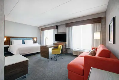 a hotel room with a bed and a couch and a television at Hampton Inn & Suites By Hilton Waterloo St. Jacobs in Waterloo