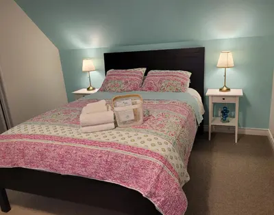a bedroom with a large bed with a pink bedspread at La Maison de Sophie in Niagara on the Lake