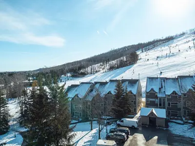 a town with snow covered buildings and a ski slope at Ski In Out Mountainside Chalet 83001 in Blue Mountains