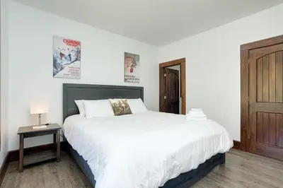 a bedroom with a large white bed and a table at Luxury Mountain Retreat with private hot tub 82958 in Blue Mountains