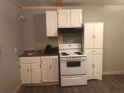 a kitchen with a white stove and white cabinets at Earthquest Lodge in Port Burwell