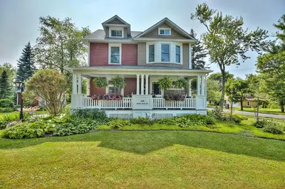 a red house with a white porch and a yard at THE YORK HOUSE BOUTIQUE Stay in Fort Erie