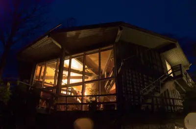 a house with a lot of glass windows at night at Stouffermill Bed & Breakfast in Algonquin Highlands